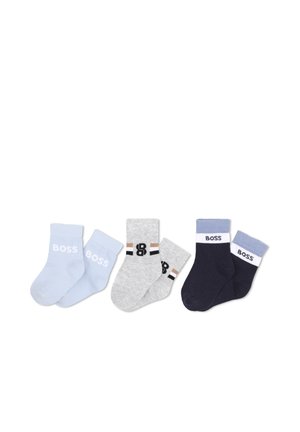 Trois paires de chaussettes pour tout-petits en bleu clair, gris clair avec des rayures noires et marron, et bleu marine foncé avec des bordures blanches et bleues, chacune marquée avec "BOSS."