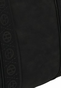 Zwarte leren tas met een gestructureerde riem met cirkelpatronen, een gladde oppervlakte en een minimalistisch design. Aangevuld met gestikte details.