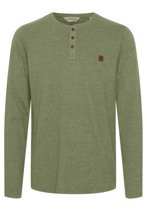 Maglia henley a maniche lunghe in cotone verde oliva tenue, con scollatura rotonda, patta con tre bottoni e un piccolo patch con logo marrone.