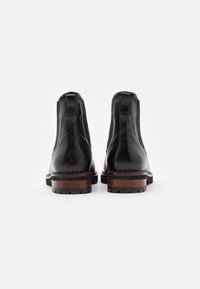 Schwarze Leder Stiefeletten mit glatter Oberfläche, elastischen Seiteneinsätzen und braunen Holzabsätzen. Verfügt über eine Schlaufe an der Rückseite für ein einfaches An- und Ausziehen.