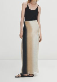Gonna maxi in un tessuto morbido e leggero con una sfumatura ombre dal nero al beige. Abbinata a una canotta nera aderente e sandali flat.