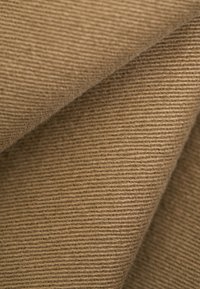 Primer plano de tela marrón acanalada doblada que muestra un patrón de tejido texturizado y fibras suaves.