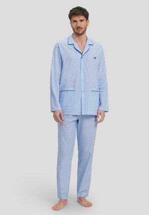 Conjunto de pijama de color azul claro con lunares negros, camisa de botón de manga larga con dos bolsillos y pantalones a juego. Textura de tela suave.