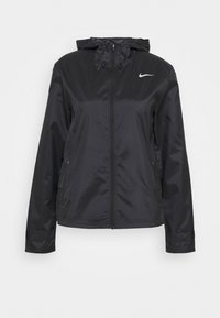 Veste en nylon noir avec fermeture éclair à l'avant, capuche et logo Nike réfléchissant. Présente une surface texturée et deux poches latérales.