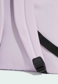 Zaino lilla chiaro in tessuto testurizzato, con accenti di tracolla nera e un'etichetta logo nera sul lato.