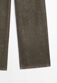Pantalon en denim vert olive foncé avec une coupe droite. Présente une texture subtile et des coutures standard le long des coutures sans qu'aucun élément métallique visible ne soit apparent.