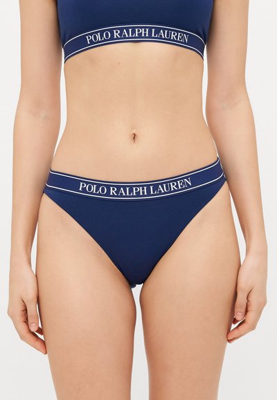 Námořnický modrý bralet s širokým elastickým páskem, na kterém je bíly text "POLO RALPH LAUREN". K tomu ladící námořnické nízké slipy s podobným páskem.