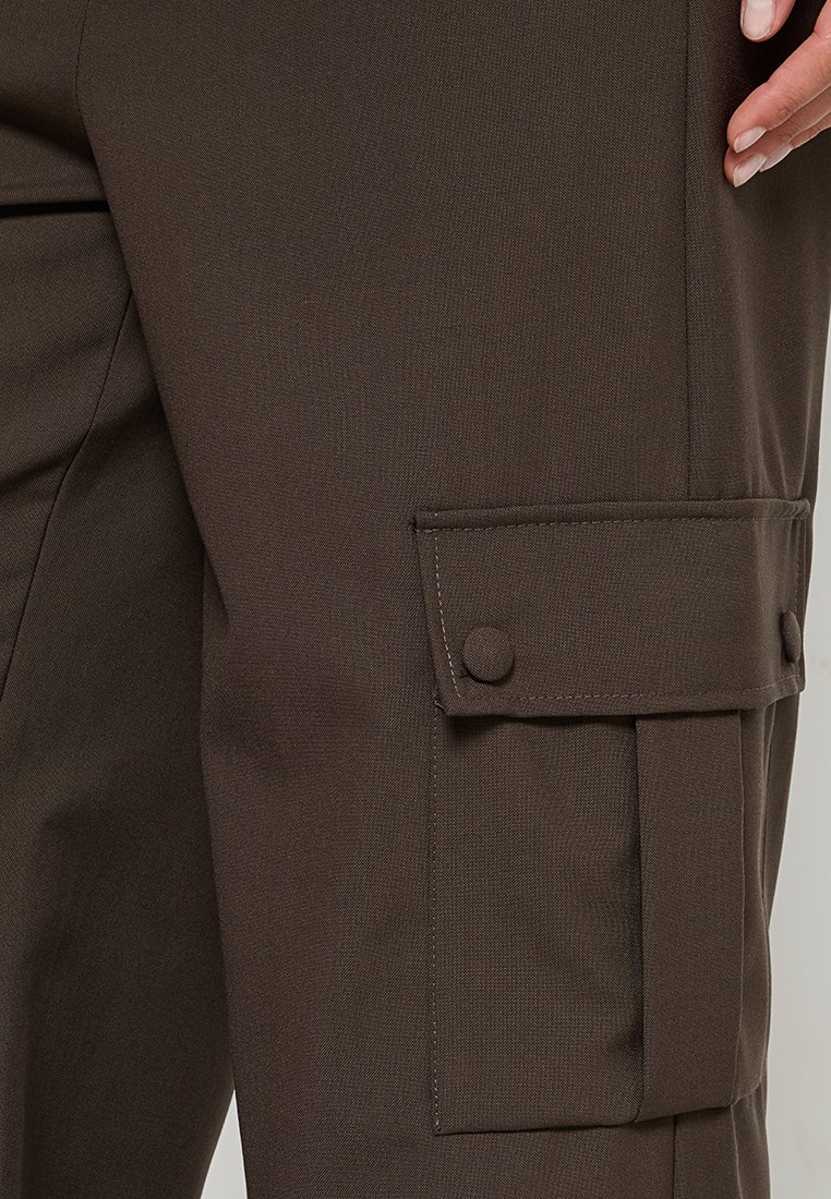 Braune Cargo-Hosen aus glattem Stoff, mit einer seitlichen Tasche mit Knopfverschluss und flachen Nähten. Das Design ist funktional und utilitaristisch.