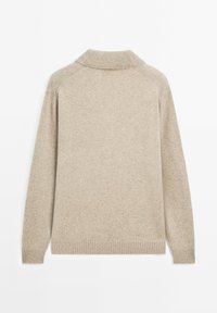 Beige trui met een geribde kraag en zoom. De stof lijkt zacht en gestructureerd, met een losse pasvorm en raglanmouwen.