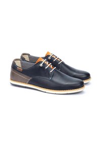 Scarpe da uomo in pelle nera con accenti marroni. Presentano cuciture bianche, suola beige e una fodera interna a righe.
