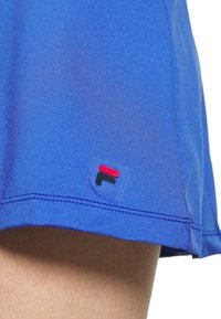 Modré sportovní kraťasy z hladké tkaniny, s malou červenou a černou značkou na lemu a kontrastním šitím.