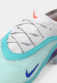 Athletic shoe featuring a light blue textured upper, gray laces, and turquoise accents. Distinct Nike logo in blue on the side.