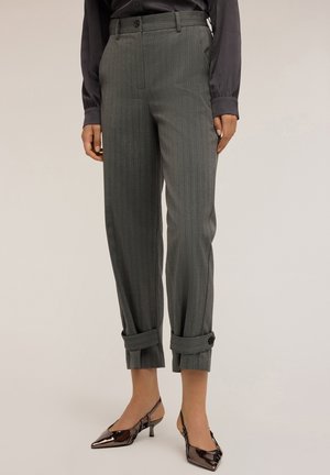 Pantaloni a righe grigi con vita alta, orli arrotolati fissati da bottoni, abbinati a tacchi a punta lucidi. Tessuto dalla texture liscia.