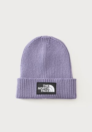 Lawendowa dzianinowa czapka z podwijanym rondem i czarną prostokątną naszywką z białym logo "The North Face" na jednolitym tle.