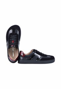 Baskets basses noires avec des accents rouges en texture peau de serpent au talon et des lacets noirs, vues de côté et de dessus.