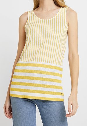 Hihaton keltavalkoraidallinen pusero pyöreällä pääntiellä, yhdistettynä sinisiin farkkuihin, kuvattuna olkapäistä lantiolle.