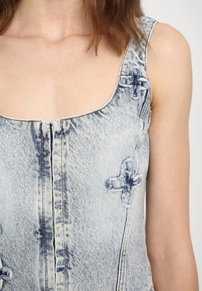 Light blue denim top with a square neckline, featuring vertical seams, cross-stitch accents, and a partially zipped front. Smooth texture.