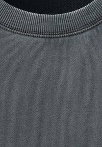 Siva majica s kružnim izrezom ima rebrast izrez in teksturirano pletenino, ki zagotavlja gladko površino in enakomerne šive.