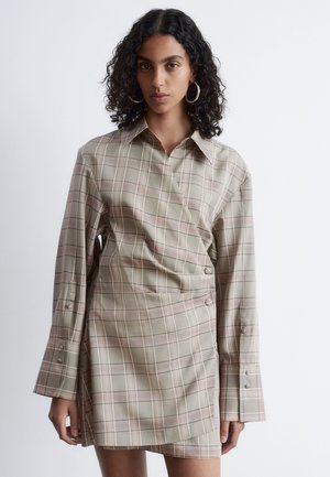 Checked wrap dress in beige and light green, with long sleeves and button details. Soft fabric texture, featuring pink and grey lines in the pattern.