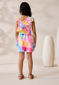 Salopetă colorată fără mâneci, cu accente drapate pe umeri, talie elastică și un model tie-dye în nuanțe de roz, albastru și galben.