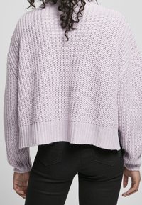 Maglione oversized lilla lavorato a maglia con texture a coste, spalle scese e orlo corto. Presenta una vestibilità ampia e maniche a sbuffo.