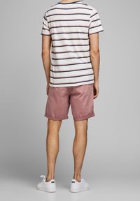 Pasiasta, krótki t-shirt w kolorze kremowym i granatowym, zestawiony z jasnoróżowymi szortami. Białe trampki dopełniają outfit. Casualowy design i dopasowanie.
