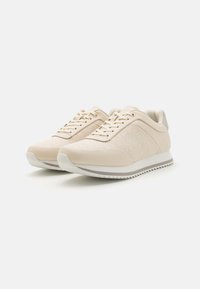 Scarpe sportive beige con upper in tessuto testurizzato, accenti lisci a contrasto, punta rotonda, lacci piatti e suola in gomma striata.