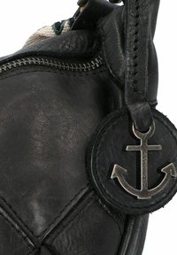 Borsa nera in pelle con texture trapuntata, caratterizzata da un charm rotondo con un design di ancora e hardware in metallo. Chiusura con zip lungo la parte superiore.