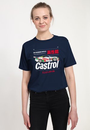 Frau trägt ein marineblaues T-Shirt mit einer Grafik eines Rennwagens, dem "Castrol"-Logo und japanischem Text zur Bewerbung von Hochleistungsmotoröl.