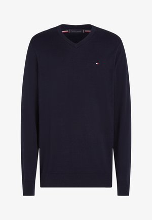 Temno modra jopica z v-izrezom in rebrastimi manšetami ter spodnjim robom. Iz mehke pletene tkanine, z majhnim logotipom na prsnem delu.