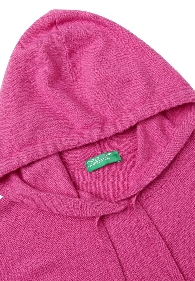 Różowy dziany hoodie z zieloną metką "United Colors of Benetton" wszytą wewnątrz kołnierza.