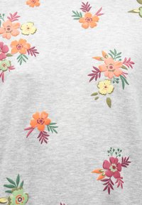 Šedá tkanina s pestrofarebnou kvetinovou výšivkou v ružovej, oranžovej a žltej farbe, so zelenými listami a rôznymi kvetinovými tvarmi rozmiestnenými po celom povrchu.