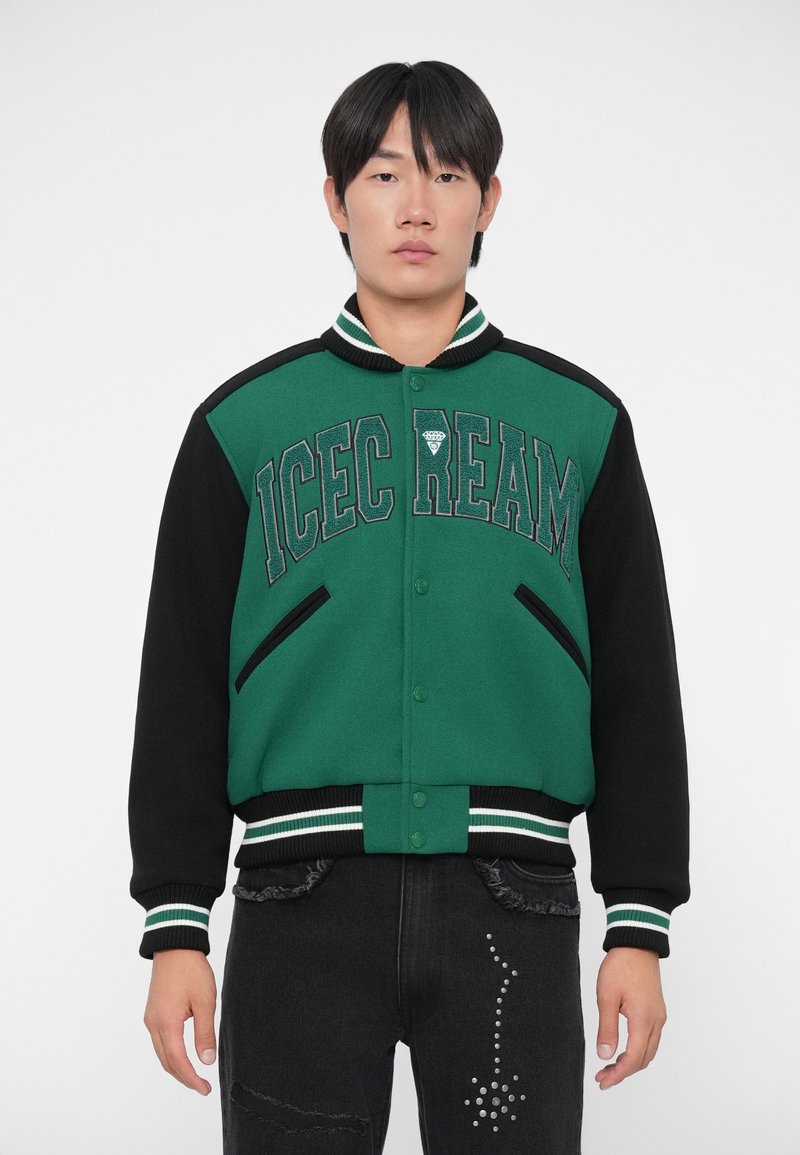 Giacca varsity verde e nera con la scritta "ICECREAM", bottoni a pressione, colletto e polsini a costine, e due tasche laterali.