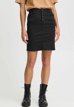 Black denim mini skirt with a high waist, featuring front buttons, side pockets, and a fitted design. Worn with black lace-up boots.
