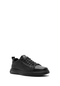 Sneaker in pelle nera con punta arrotondata, design con lacci e collo imbottito. Presenta un cuscinetto d'aria visibile e una suola in gomma testurizzata.