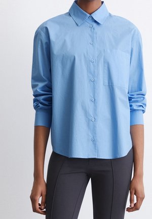 Camicia azzurro chiaro con colletto a punta, taschino sul petto e maniche lunghe. Realizzata in un tessuto morbido e leggero.