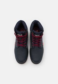 Paire de bottes Levi’s noires avec lacets rouges et col en denim rembourré, vues de dessus sur un fond blanc.