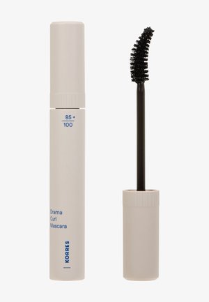 Weißer Tubus von Korres Drama Curl Mascara mit einem gebogenen schwarzen Mascara-Pinsel daneben auf einem weißen Hintergrund.