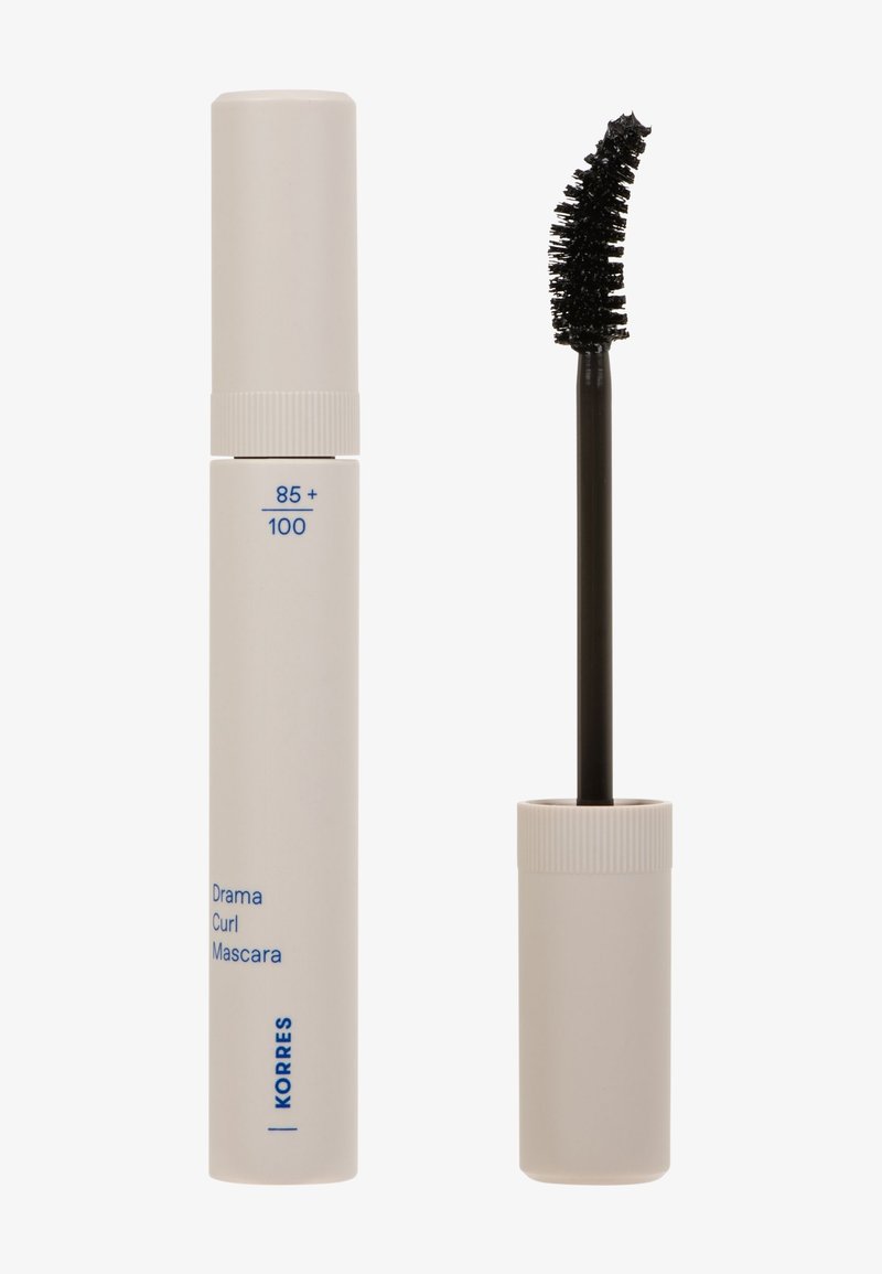 Tubetto bianco di mascara Drama Curl di Korres con scovolino curvo nero accanto su uno sfondo bianco.
