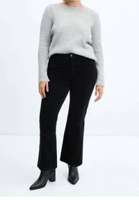 Gray knit sweater, high crew neckline; paired with black corduroy flared pants; black ankle boots with a pointed toe.