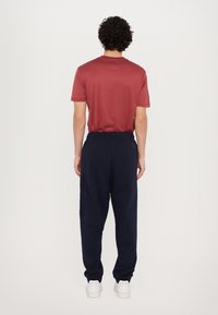 Röd t-shirt med kort ärm ihop med marinblå joggerbyxor med elastisk midja och sidofickor. Vita sneakers fulländar outfiten.