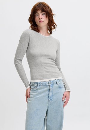Light gray long-sleeve top with a round neckline, featuring subtle texture. Paired with light blue high-waisted denim jeans.