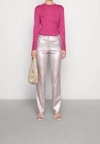 Fuchsia stickad tröja, metalliska silverfärgade raka byxor, beige handväska och sandaletter med remmar. Materialen är mjuka och reflekterande.