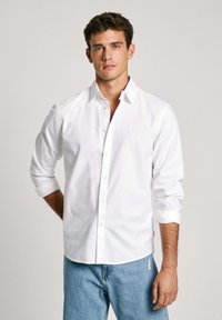 Witte button-up shirt van katoen met een gestructureerde afwerking. Voorzien van opgerolde manchetten en een subtiele logo-detail boven de linker borstzak.