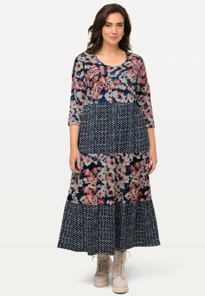 Abito lungo con motivo floreale e maniche a tre quarti; base blu navy con fiori rosa e bianchi, design a strati e parte inferiore geometrica.