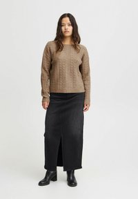 Hnedý pletený sveter s textúrovaným vzorom v kombinácii s čiernou džínsovou sukňou s predným rozparkom. Outfitu dodávajú šmrnc čierne členkové čižmy.