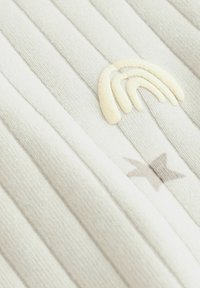 Stribet lysegrå stof med en cremegul broderet regnbue og en lille grå stjerne, med en blød, struktureret overflade.