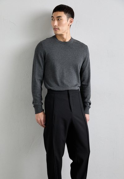 Suéter gris de punto con mangas largas, combinado con pantalones negros de cintura alta. Textura suave, diseño ajustado y líneas limpias.