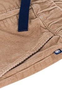 Tessuto in corduroy color sabbia con una finitura testurizzata, dotato di una cinghia intrecciata blu scuro. Include un piccolo etichetta/logo sul bordo inferiore.