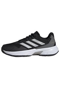 Zapatilla deportiva negra con parte superior de malla, detalles en plata y tres franjas paralelas. Cuenta con una media suela blanca y una suela exterior de goma texturizada.